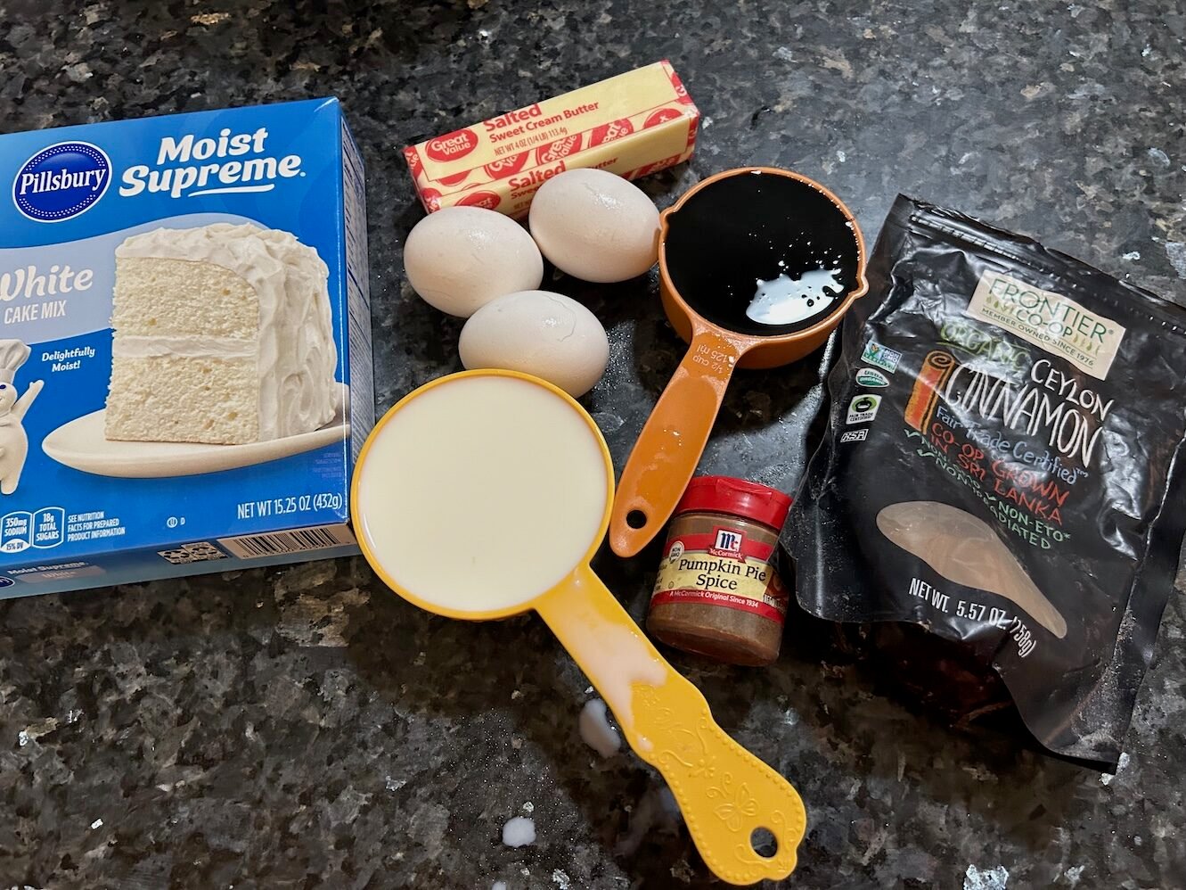 molasses cake ingredients seen from above: cake mix, milk, eggs, molasses, butter, pumpkin pie spice, cinnamon