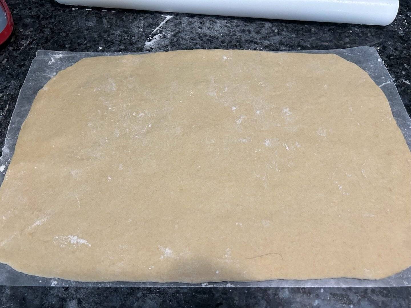 dough rolled out to make cinnamon rolls (on waxed paper)