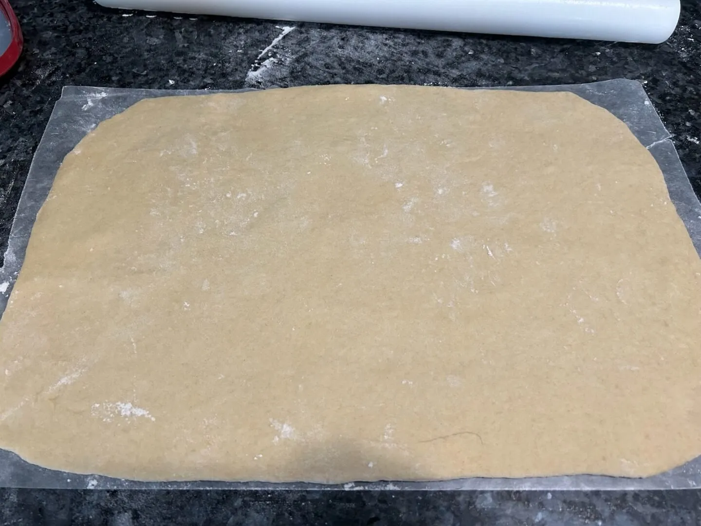 dough rolled out to make cinnamon rolls (on waxed paper)