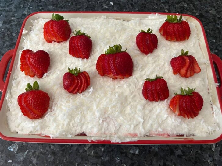 coconut and strawberries on top of Strawberry Coconut Poke Cake 