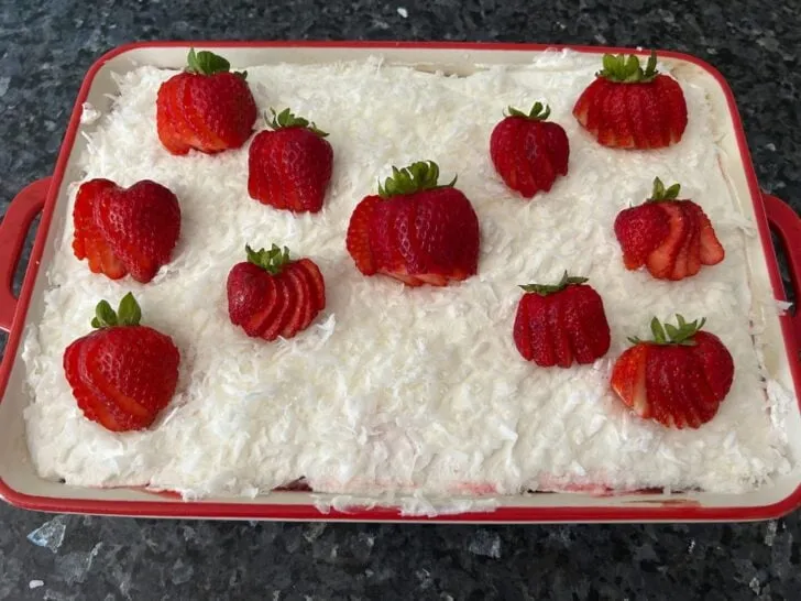 coconut and strawberries on top of Strawberry Coconut Poke Cake 