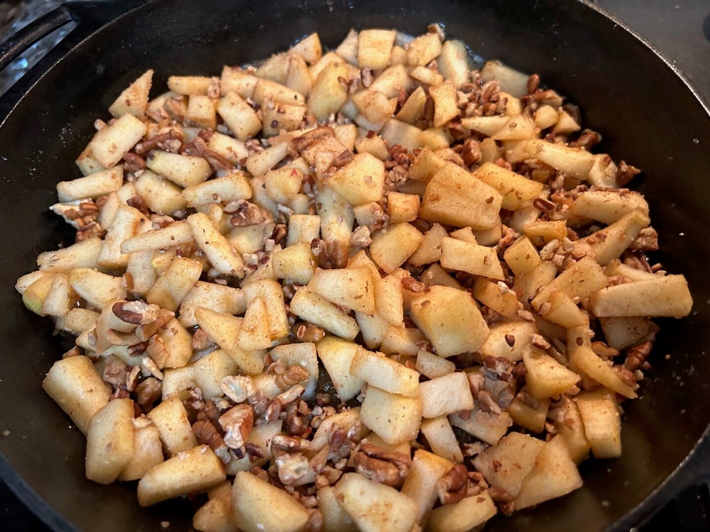 cubed apples and chopped pecans in cast iron skillet