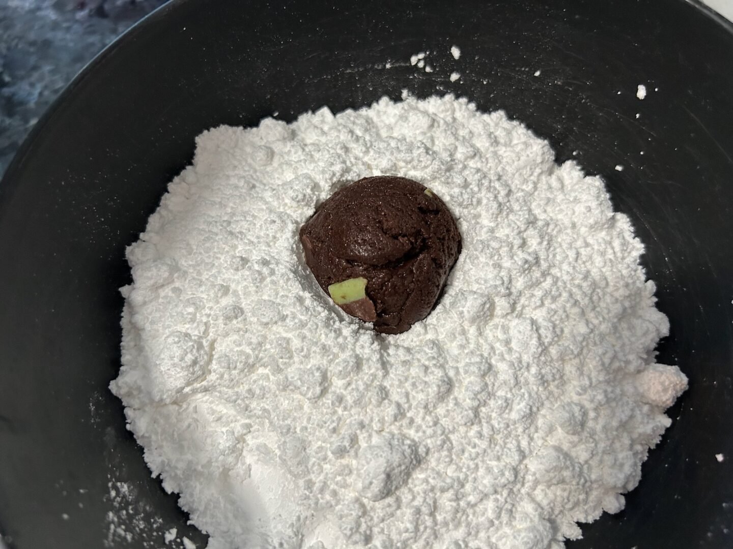 ball of cookie dough in powdered sugar