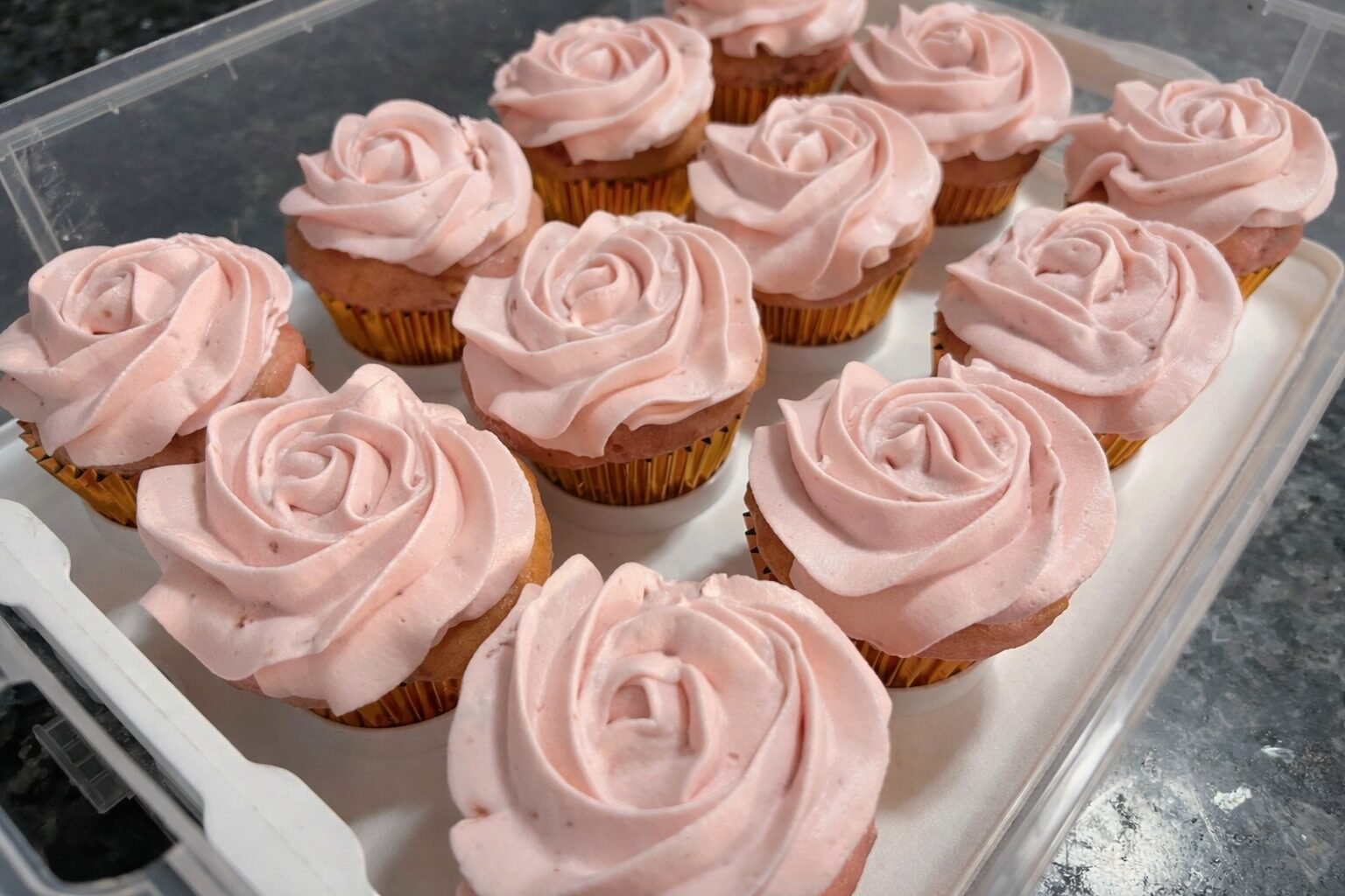 swirled pink frosting on a dozen cupcakes