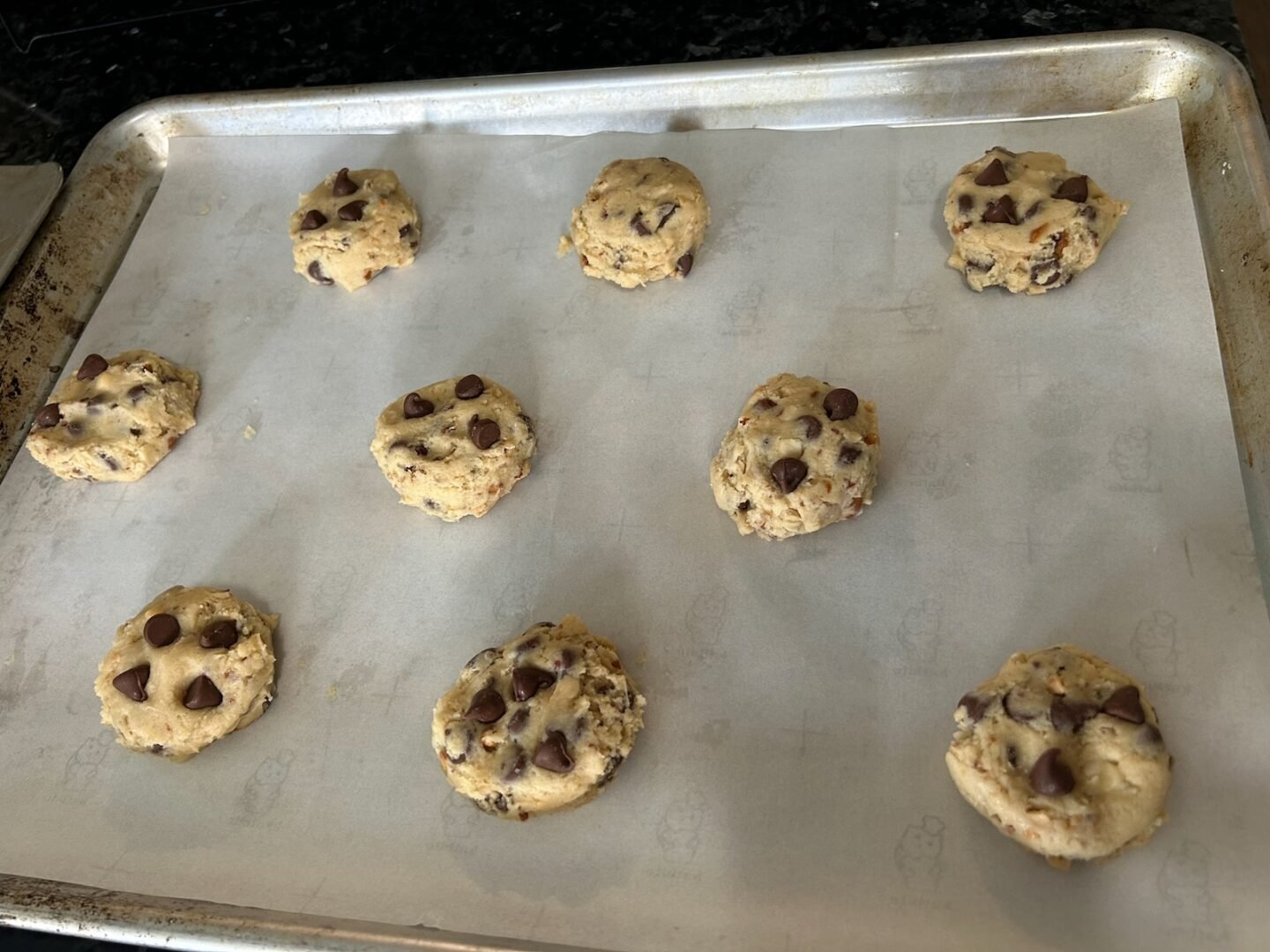 Spanish Peanut Chocolate Chip Cookie dough balls on baking sheet with extra chocolate chips added