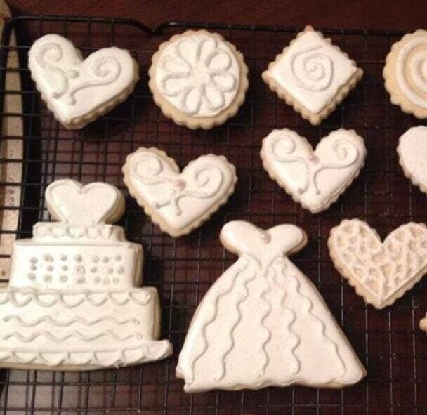 white bridal cookies shaped like wedding dresses, wedding cakes, hearts, and other shapes