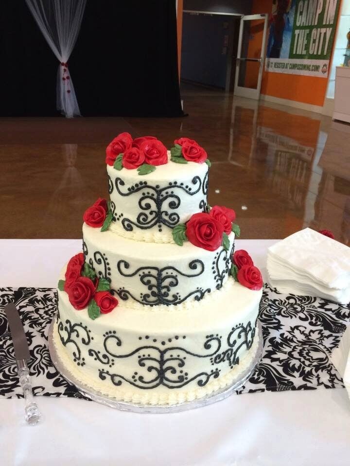 elegant wedding cake with back scrolling and red roses