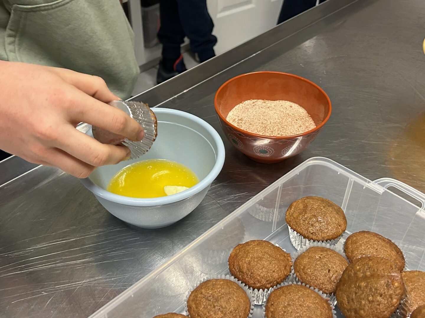 dipping banana churro muffin in butter before adding topping