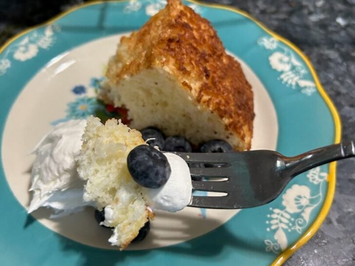 angel food cake on fork with berries and whipped cream