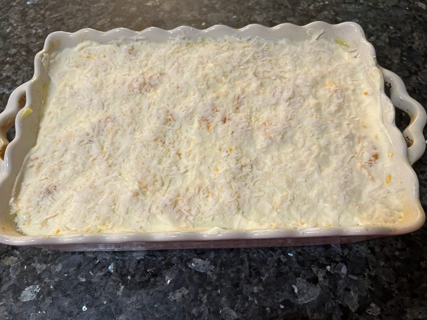 mandarin orange poke cake in pan before decorating with orange slices