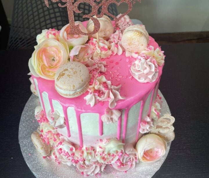 pink and white birthday cake with macarons