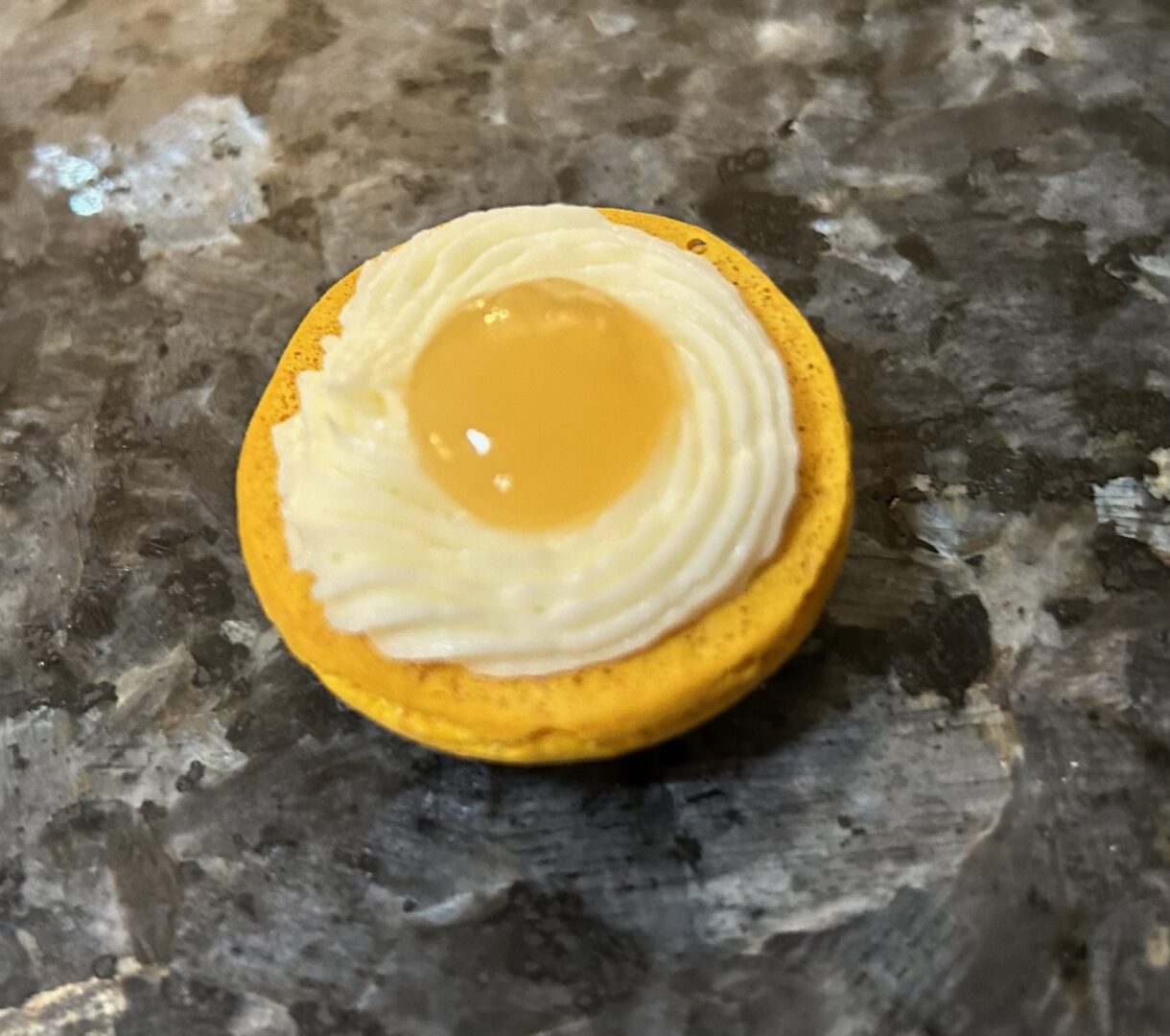 yellow macaron shell filled with buttercream rim and lemon curd filling