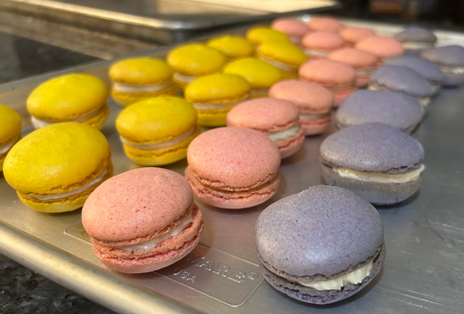 tray of freshly made macarons in yellow, pink, and purple