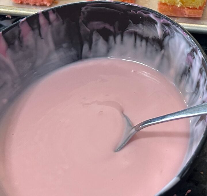 melted almond bark, thinned with oil and colored pale pink in bowl with spoon