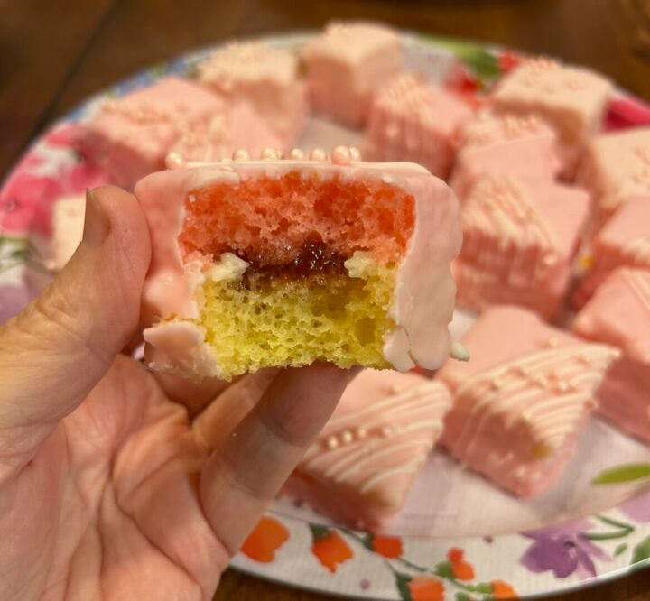interior of petit fours showing top layer of strawberry cake and bottom layer of lemon cake with icing and jam in-between
