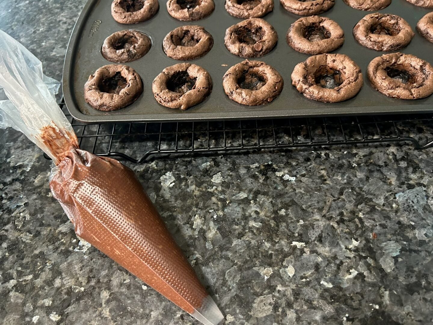 ganache in piping bag next to brownie bites in pan