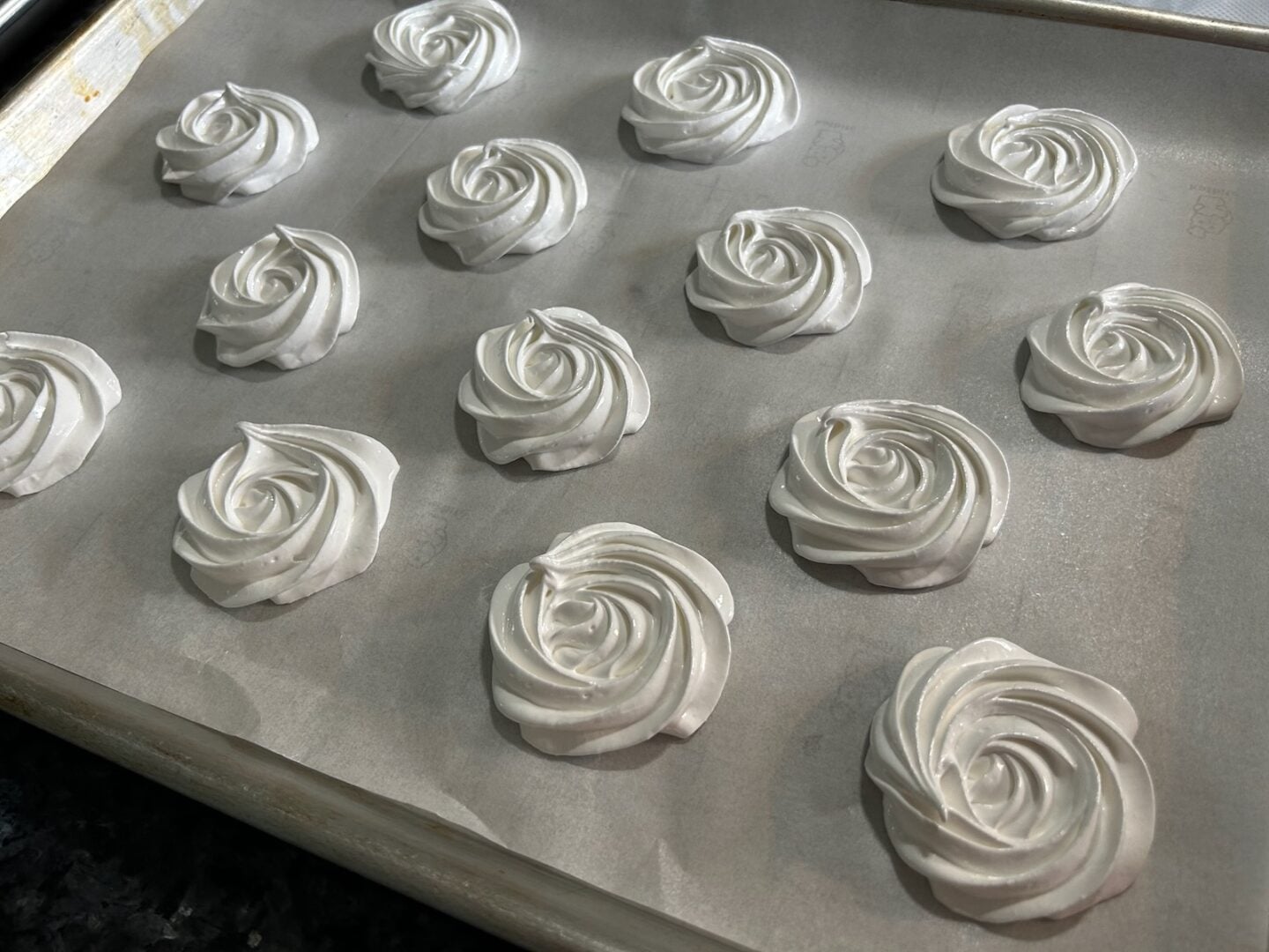 meringue rosettes piped onto baking sheet