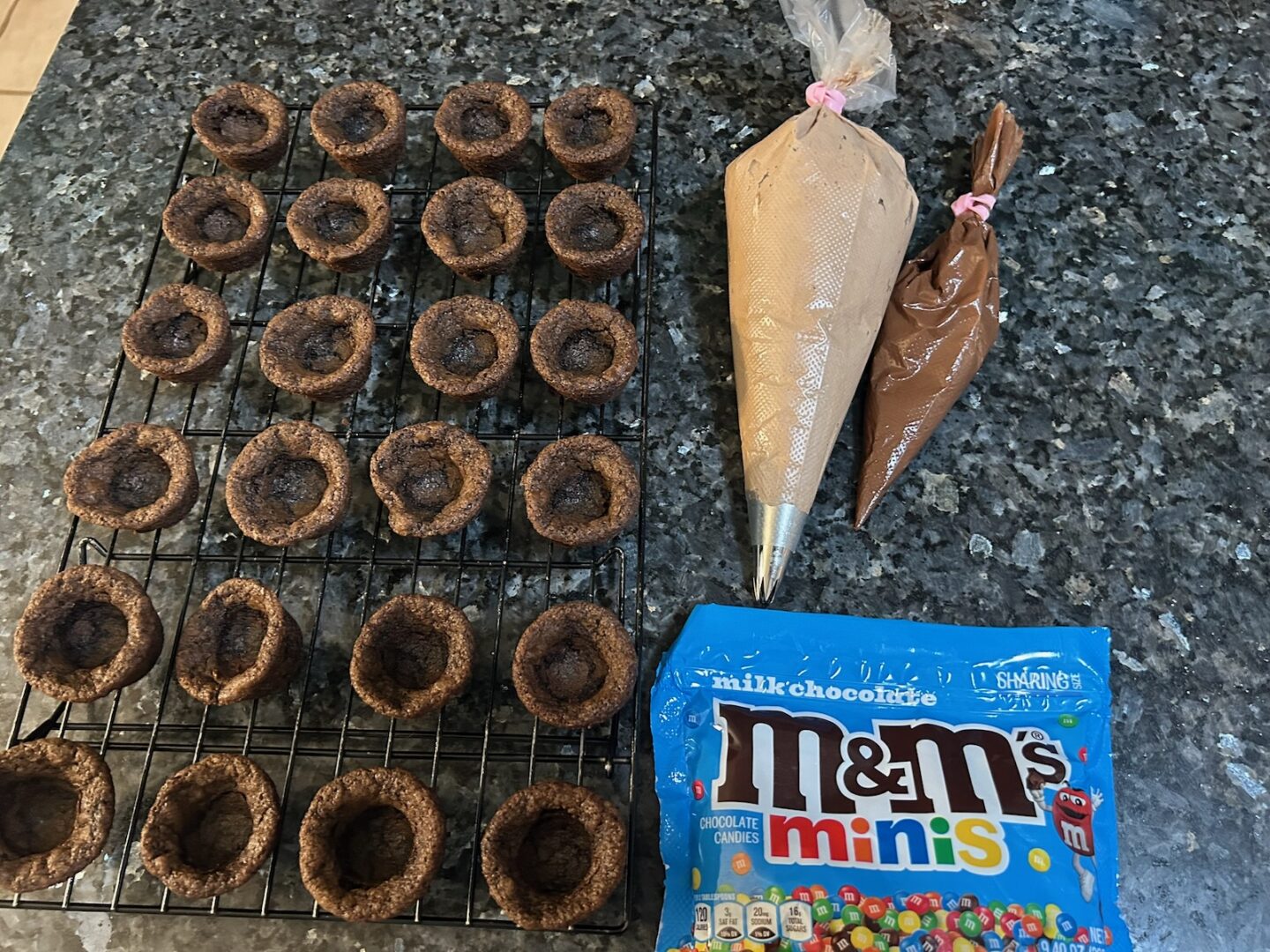cookie cups with piping bags and M&Ms nearby. 