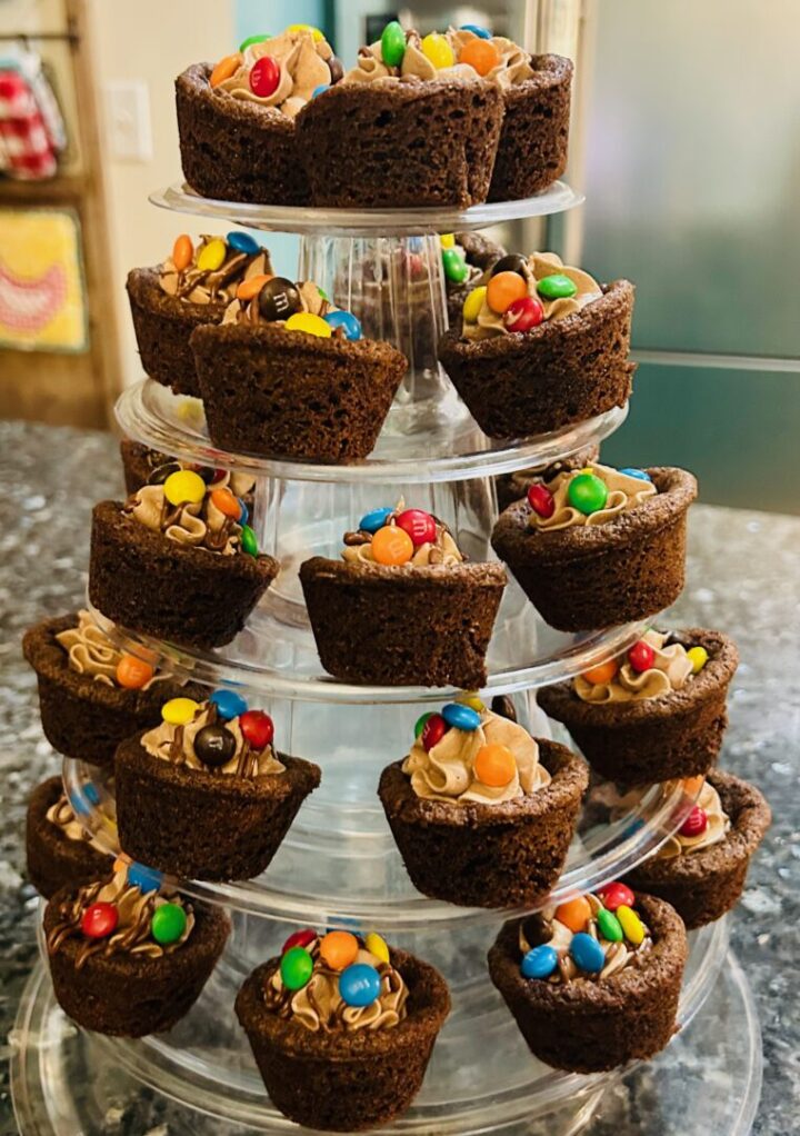 chocolate cookie cups filled with chocolate marshmallow fluff frosting and topped with mini M&Ms on tiered stand