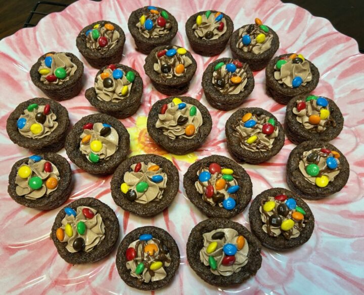 chocolate cookie cups filled with chocolate marshmallow fluff frosting and topped with mini M&Ms on serving tray
