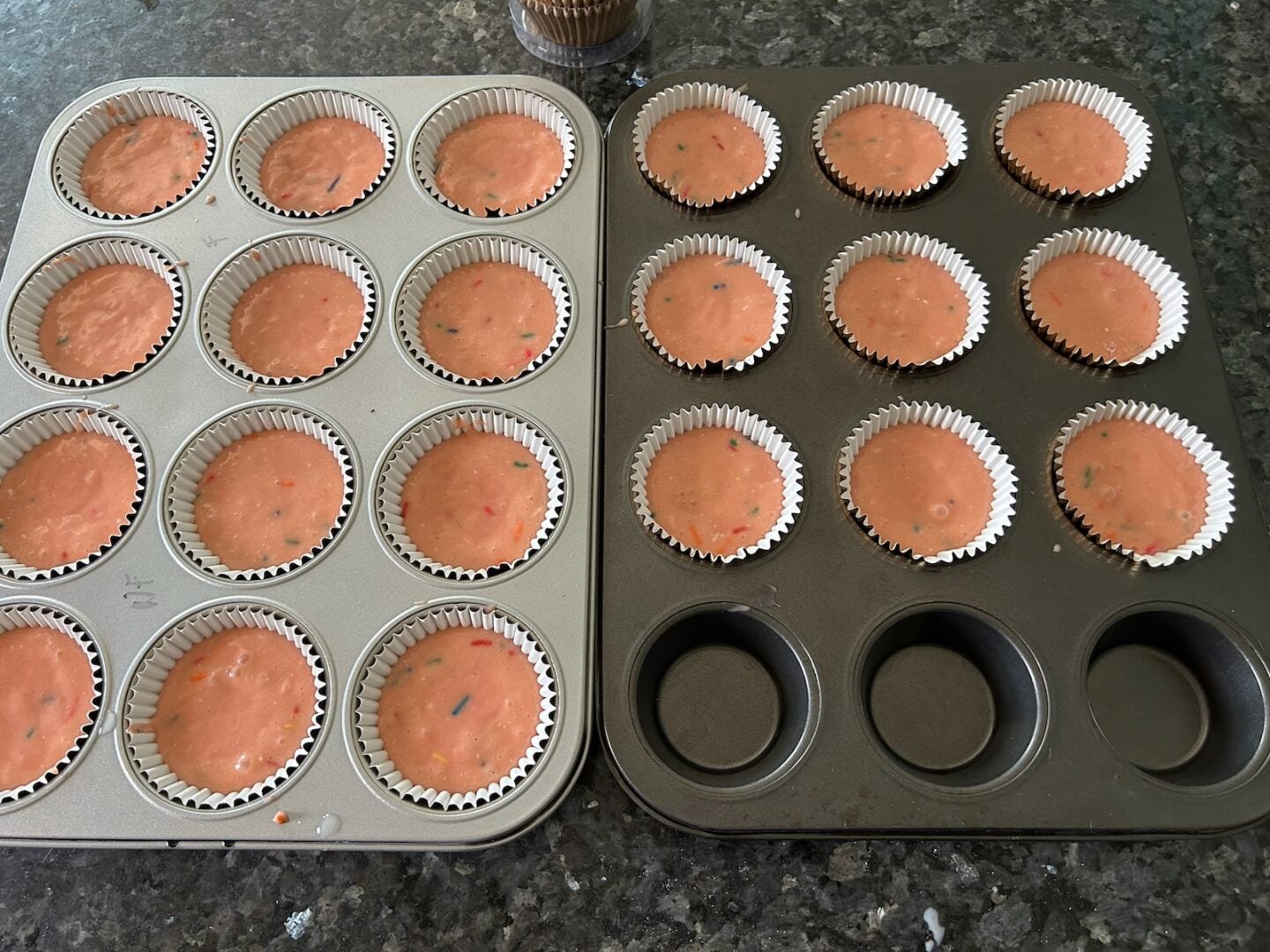 strawberry cake batter with sprinkles in muffin pan
