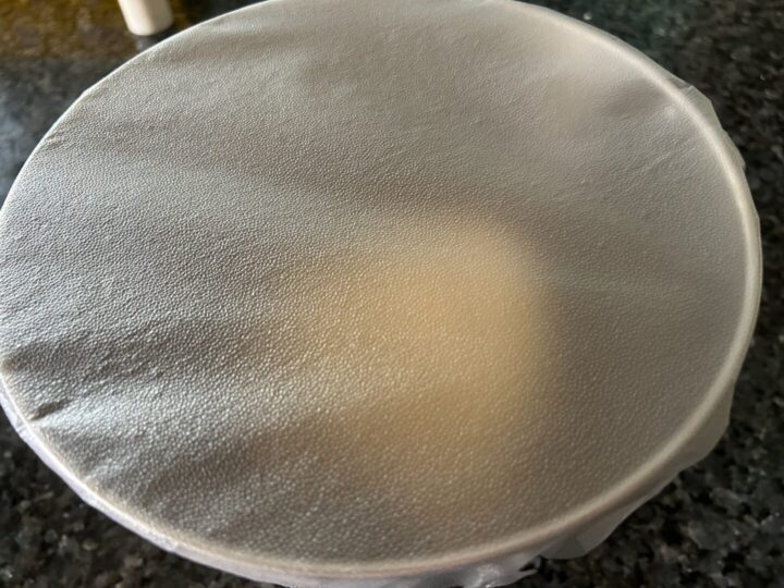 cinnamon roll dough in bowl covered in press and seal wrap