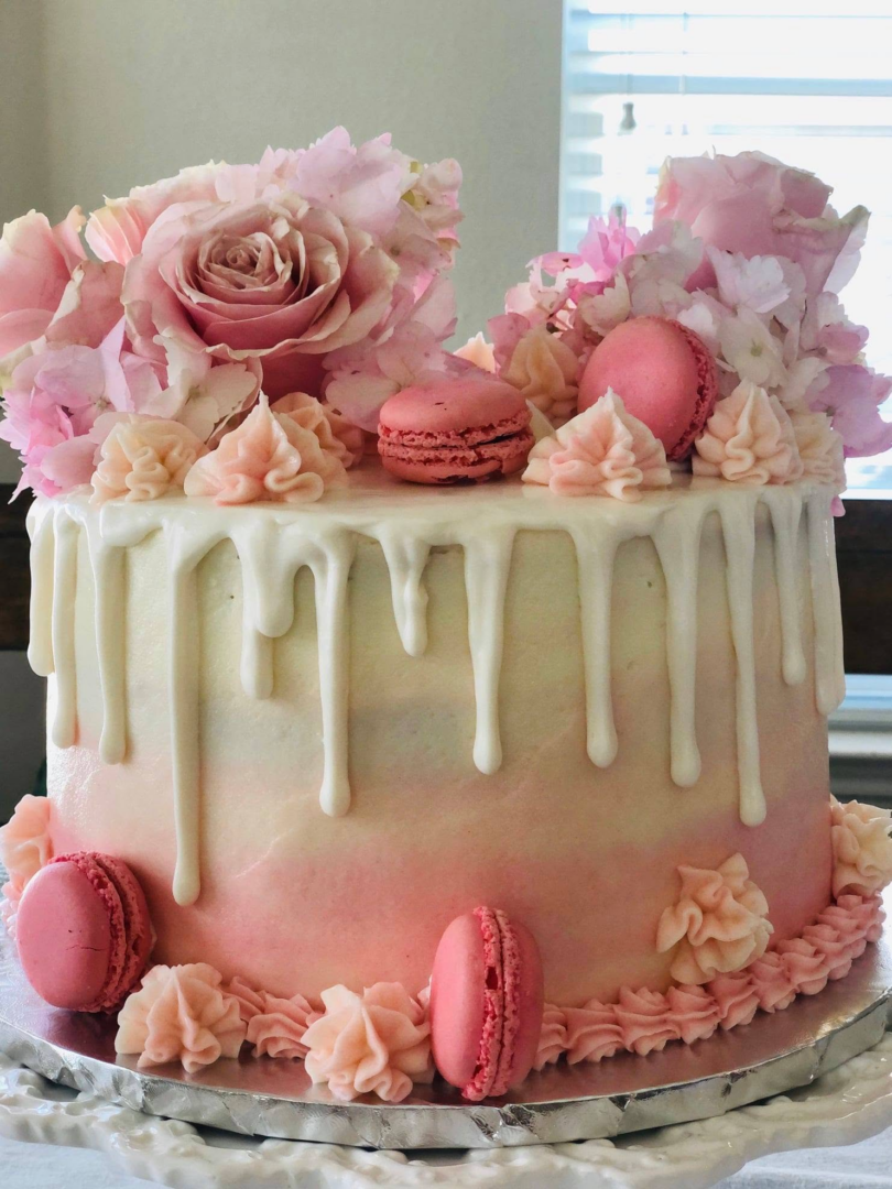 ombre cake in pink and white with macarons and white drip