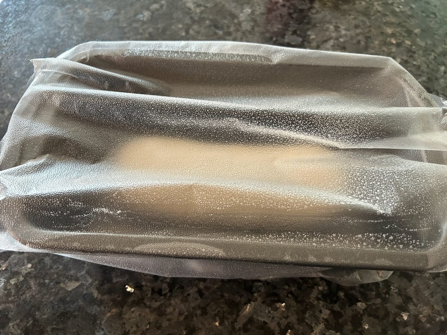 frozen bread dough in loaf pan covered with plastic wrap