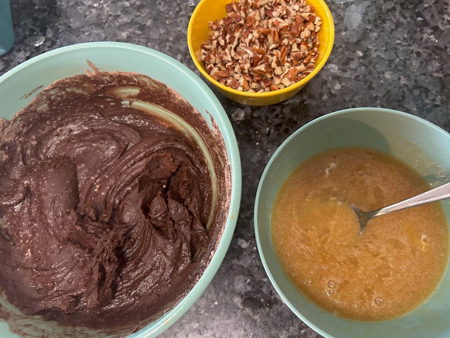 brownie batter and pecan pie filling with a bowl of pecans nearby