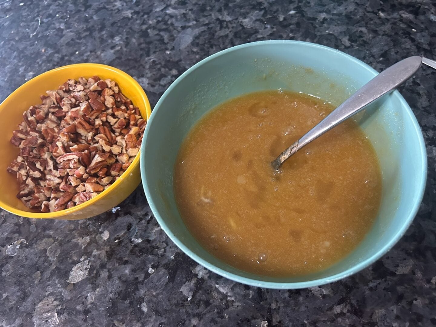 pecan pie filling with a bowl of pecans nearby