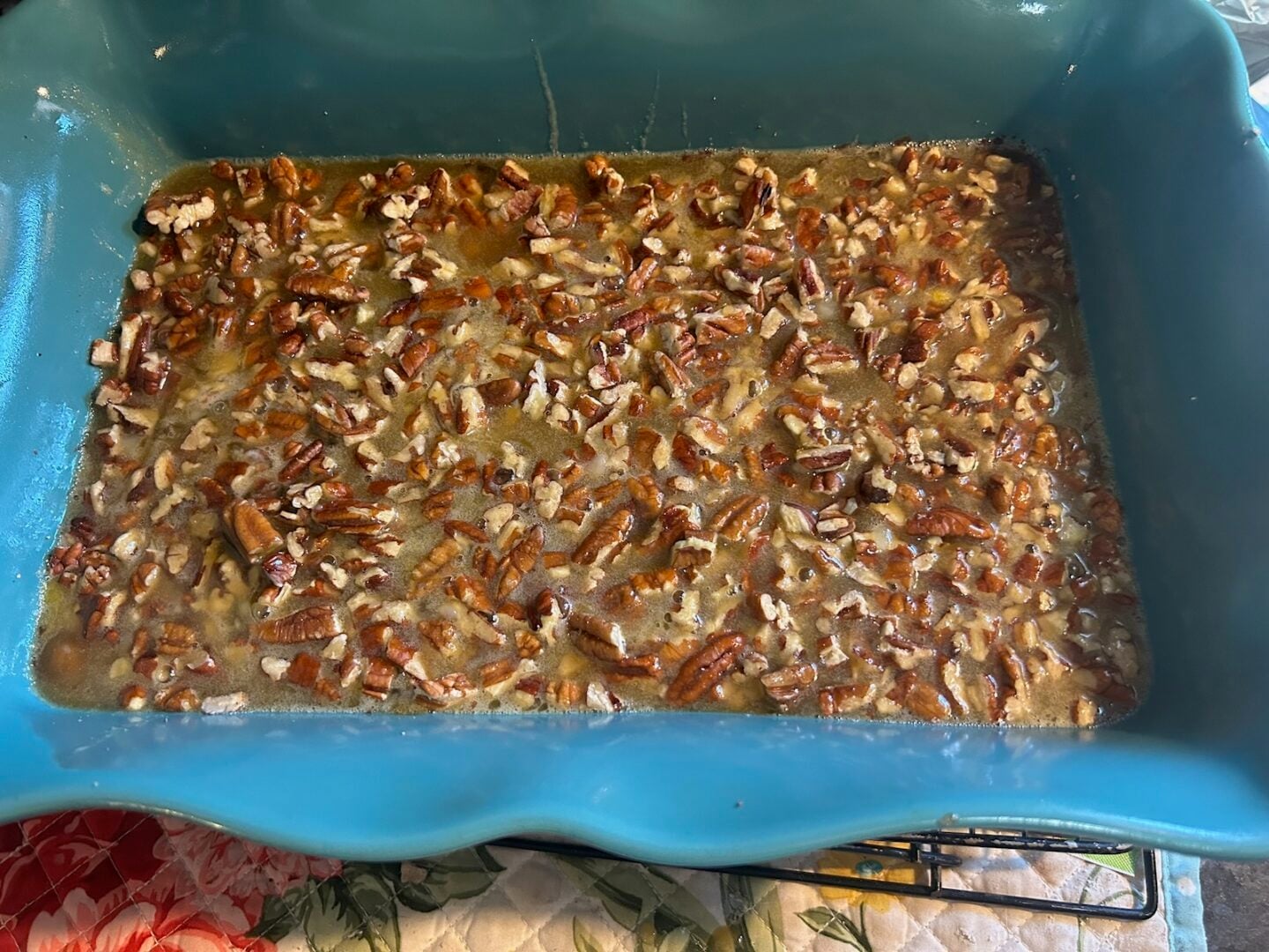 pecan pie filling poured over pecans on baked brownies