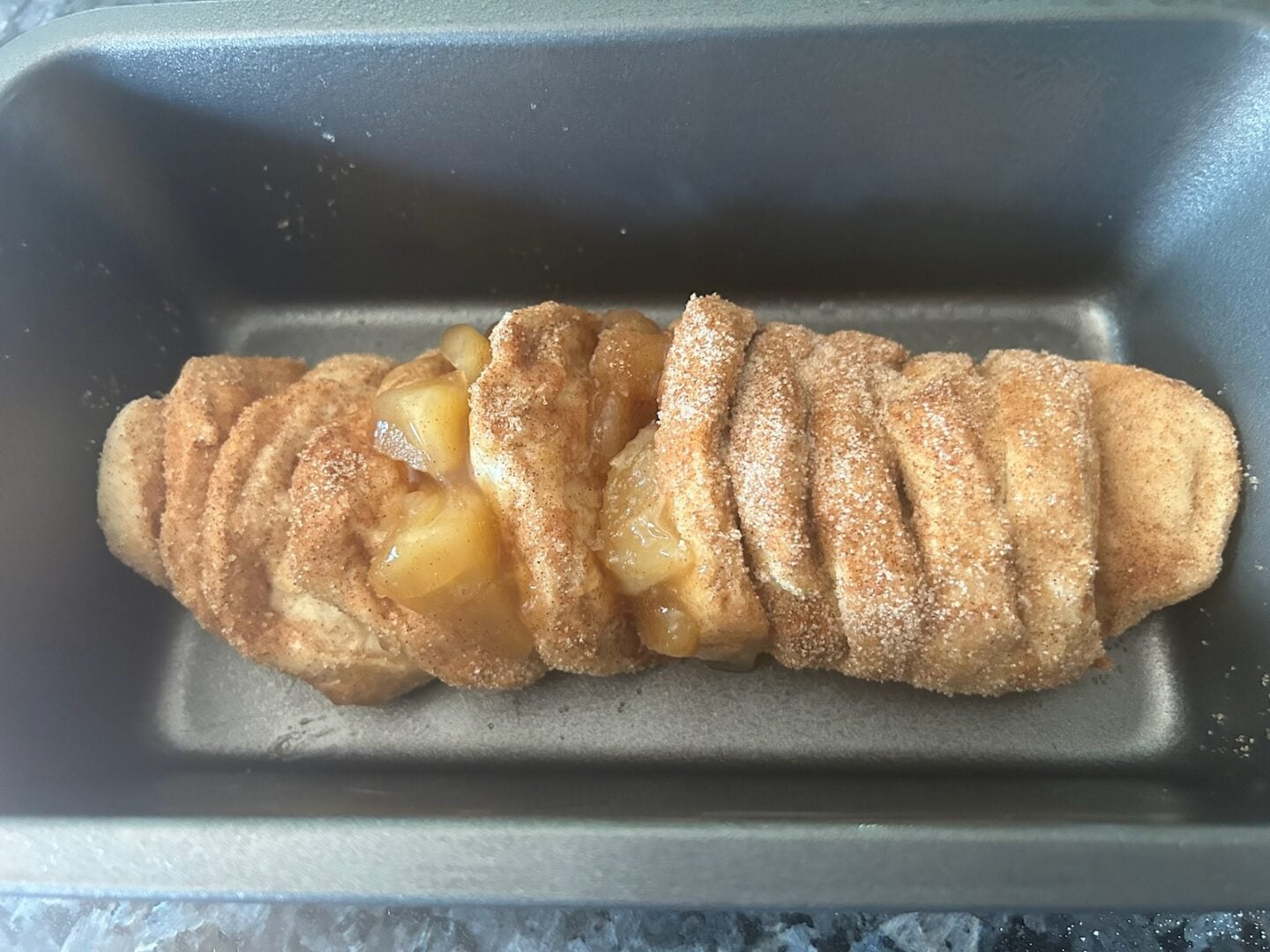 adding cinnamon sugar and caramel apples to bread loaf