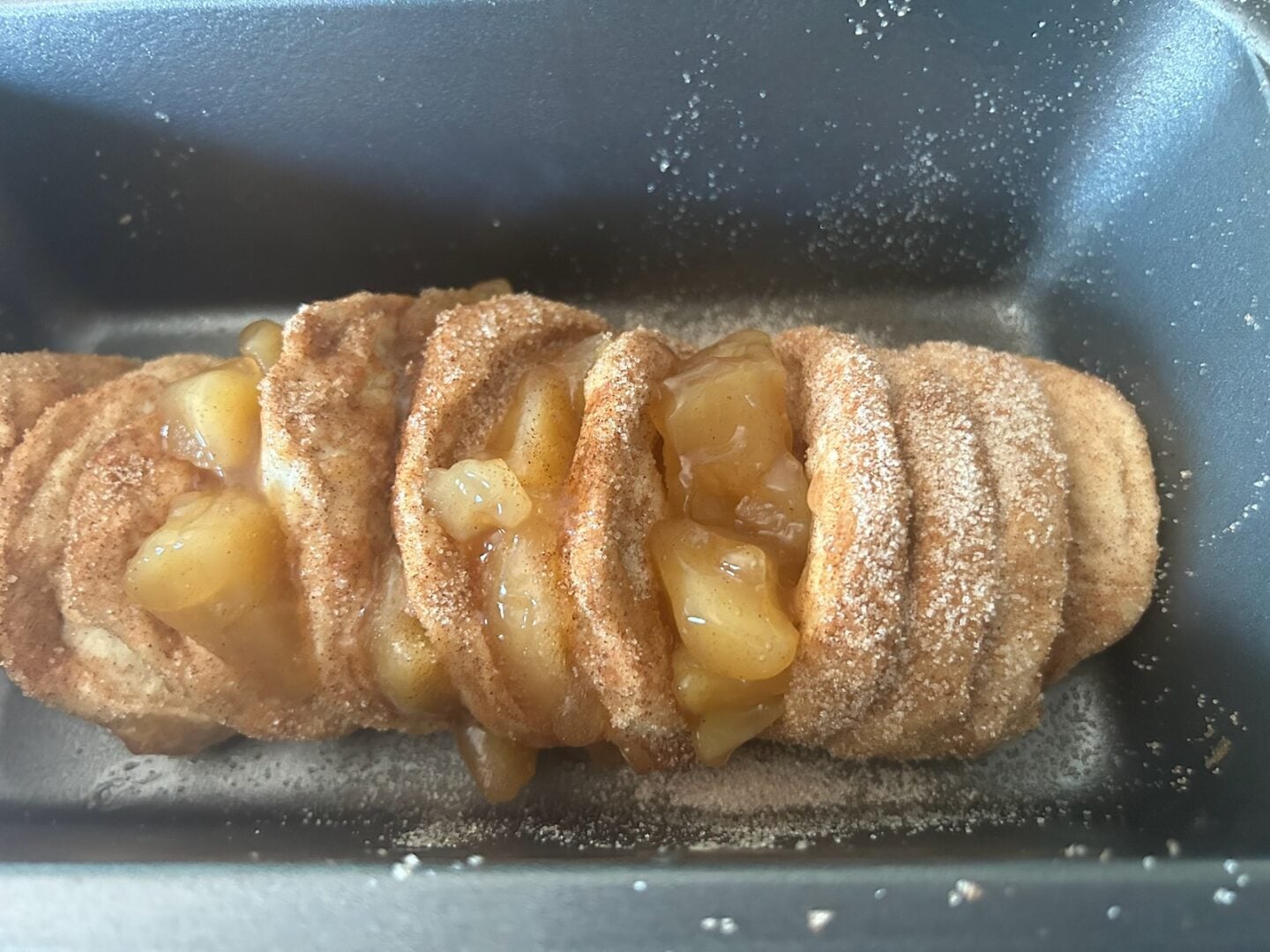 adding cinnamon sugar and caramel apples to bread loaf
