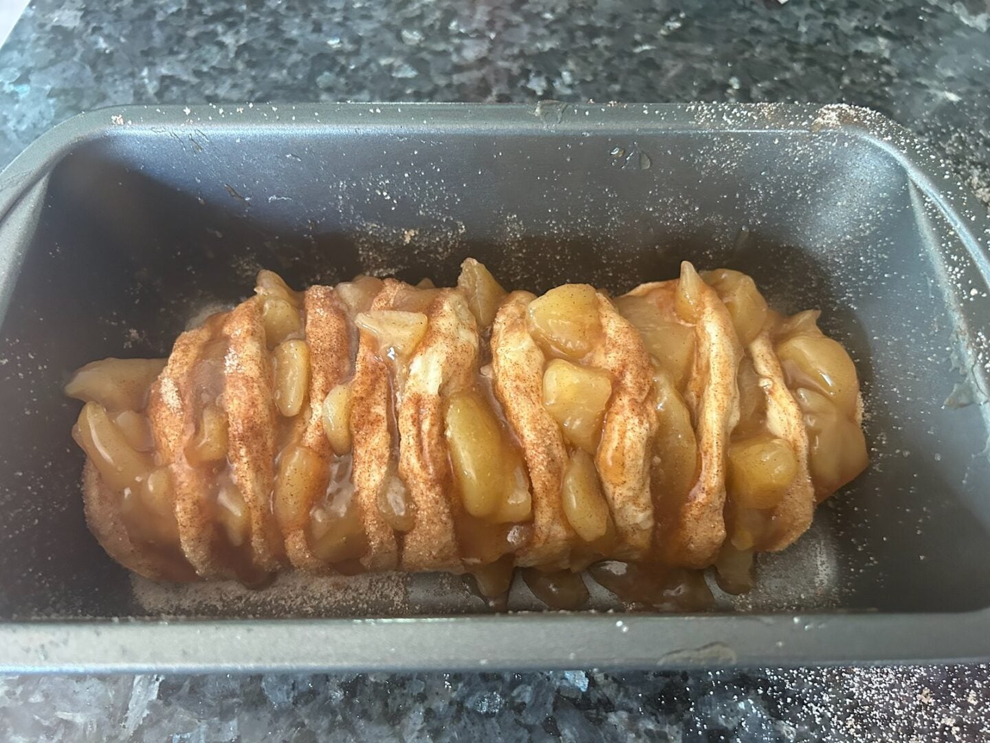 adding cinnamon sugar and caramel apples to bread loaf