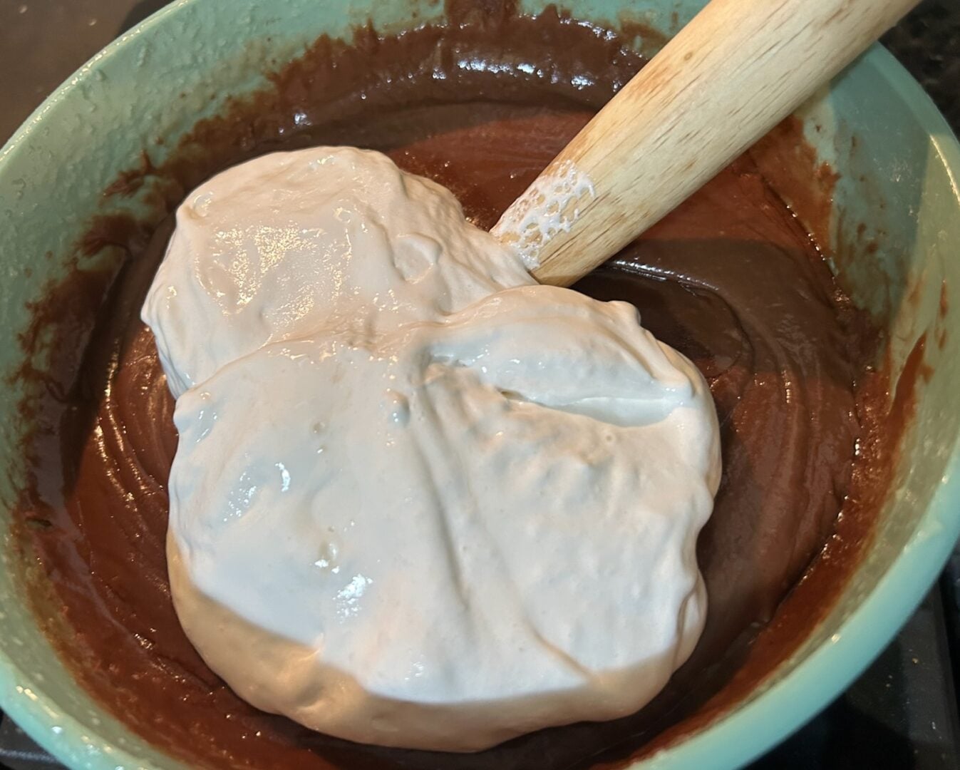 adding marshmallow cream to bowl of fudge