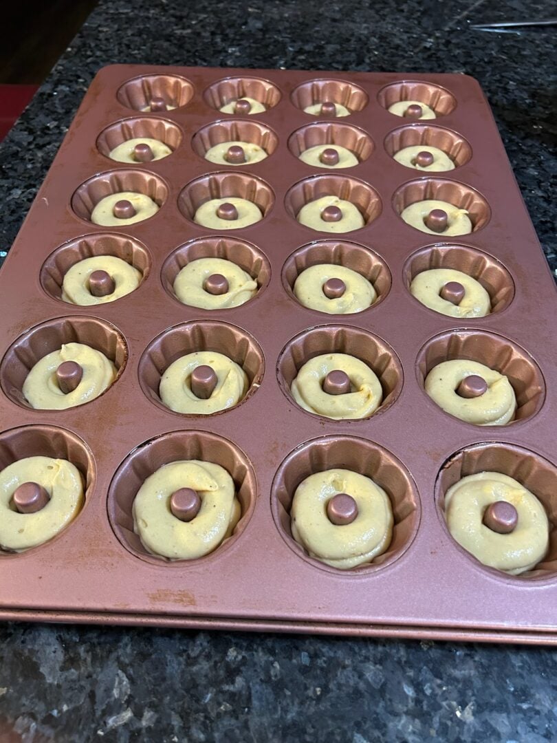 cake batter piped into mini bundt pan