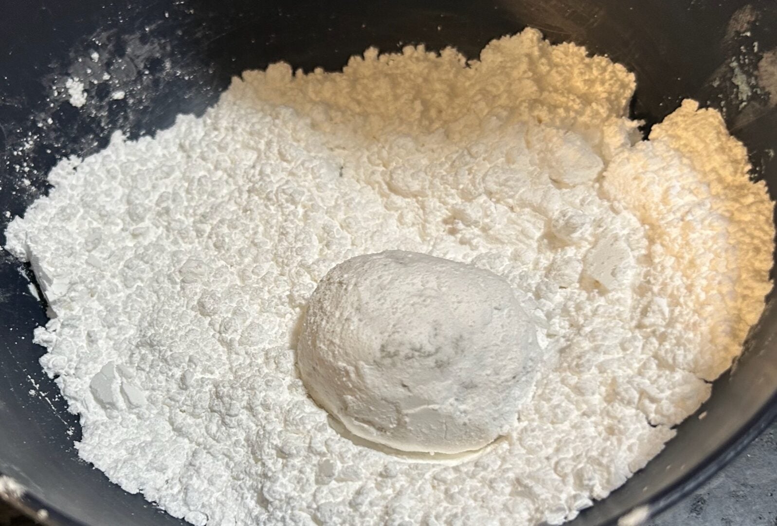 rolling cookie dough balls in powdered sugar