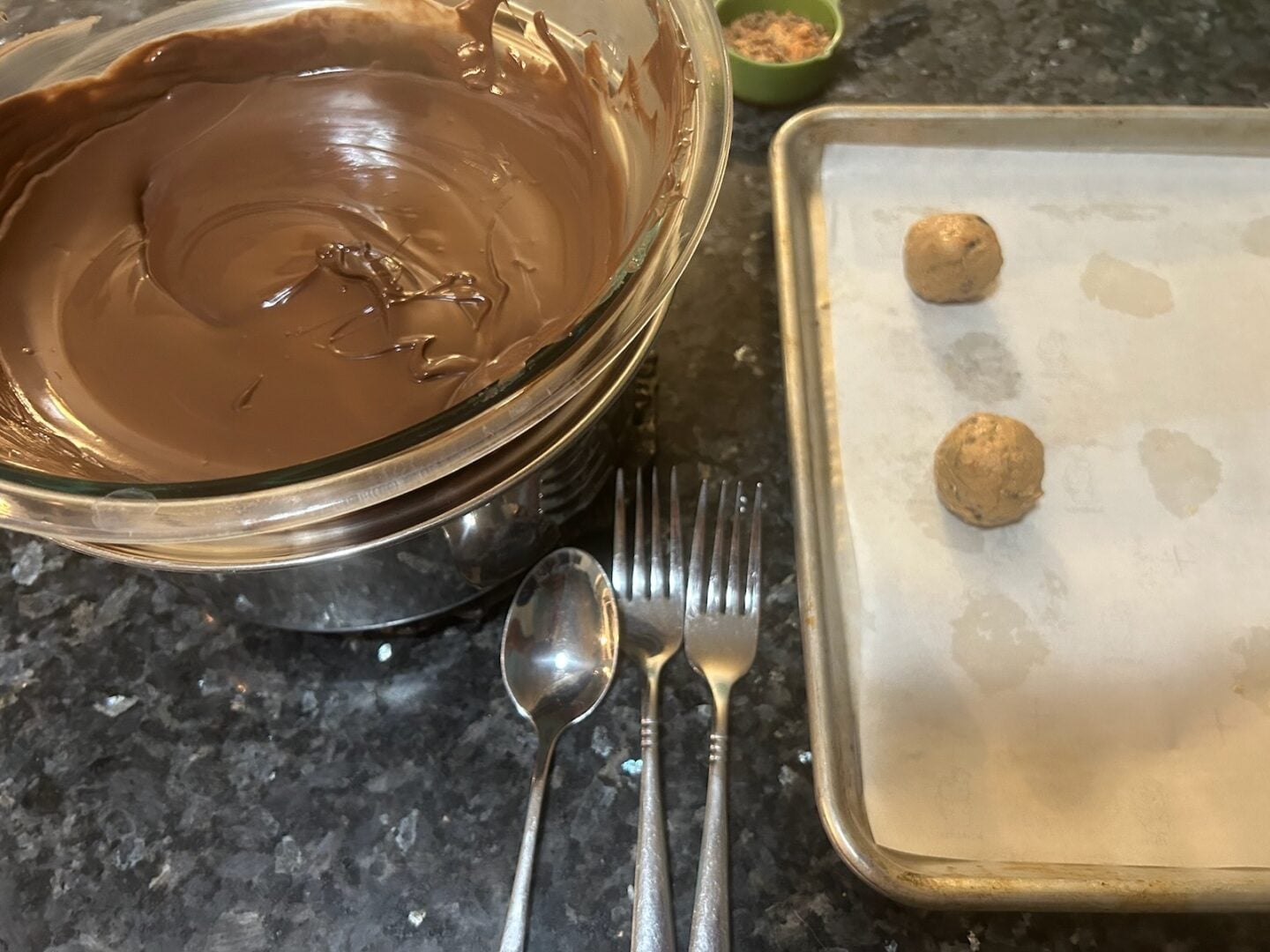 melted chocolate in double boiler with truffle balls nearby